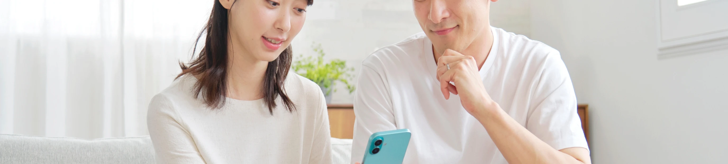 自宅のリビングでスマートフォンの画面を見つめる男女