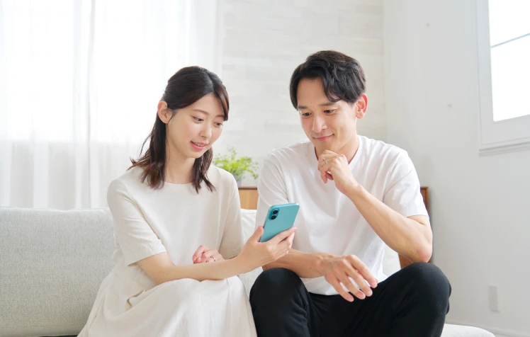 自宅のリビングでスマートフォンの画面を見つめる男女