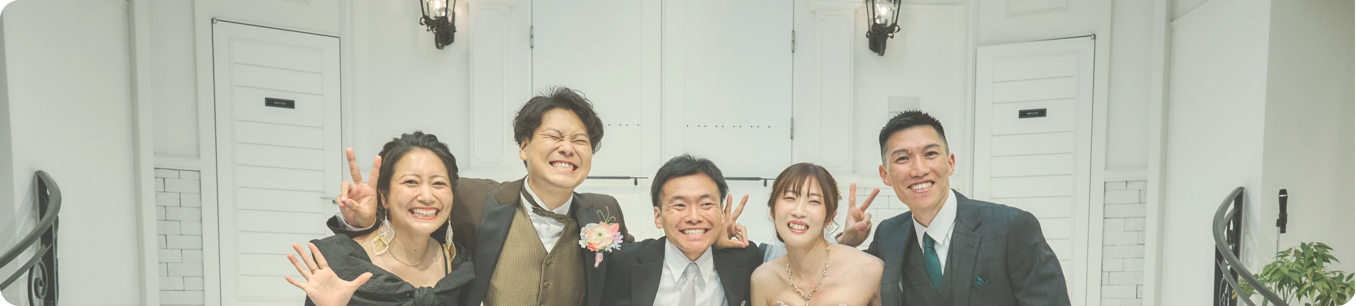 披露宴会場で新郎新婦とゲストが笑顔で記念撮影している様子