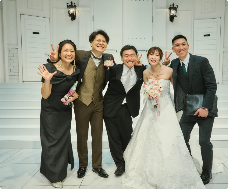 披露宴会場で新郎新婦とゲストが笑顔で記念撮影している様子