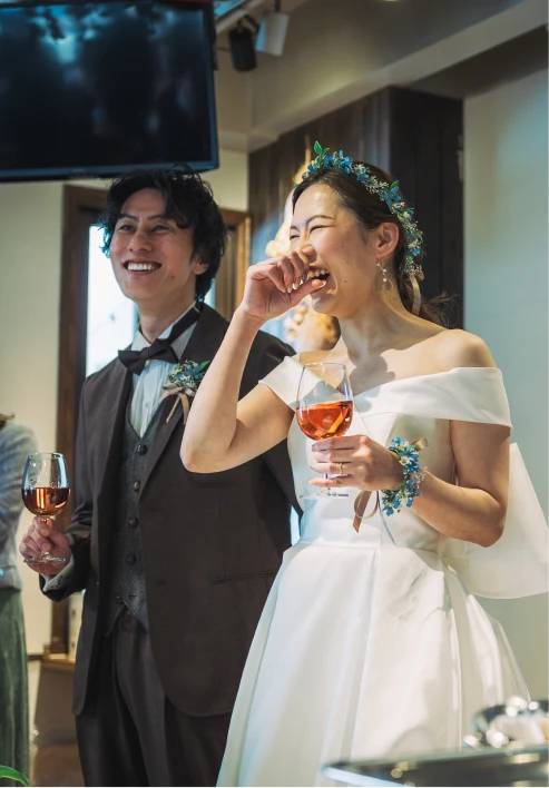 新郎新婦が笑いながらグラスを持っている様子